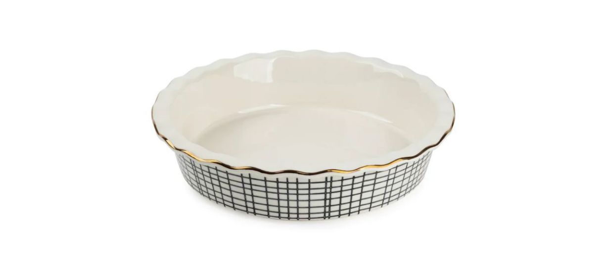 a white stoneware pie dish with scalloped gold edges and a black and white crosshatch pattern on the sides