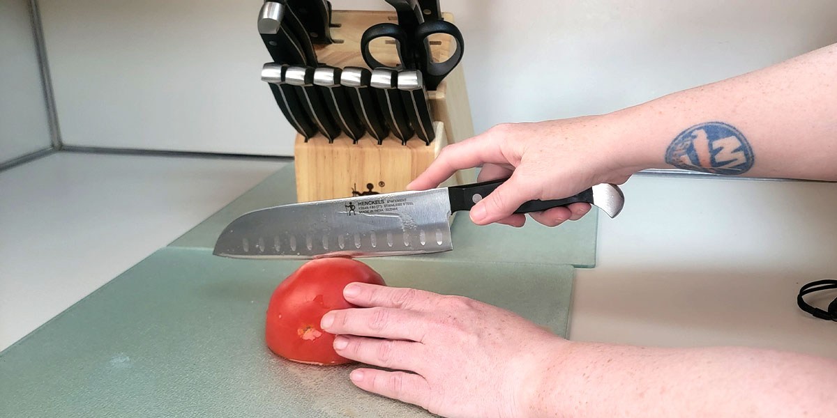 Person using Henckels Premium Quality knife to slice tomato Person using Henckels Premium Quality knife to slice tomato