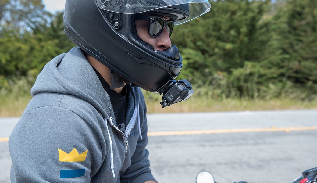 A person wearing a Best Reviews sweatshirt sits atop a motorcycle while wearing a motorcycle helmet.