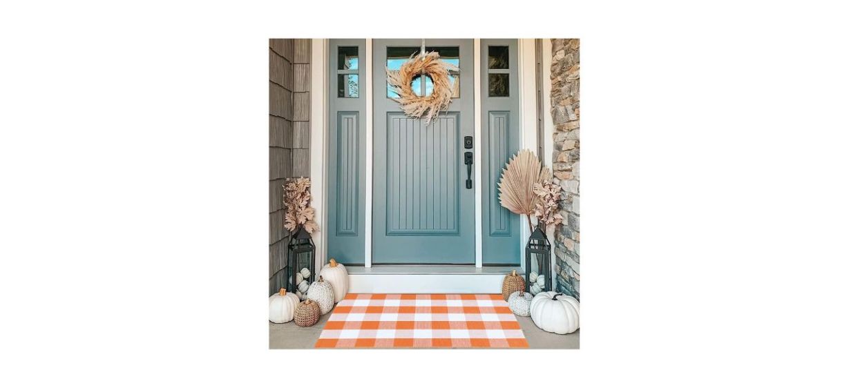 An orange and white buffalo plaid rug on a porch