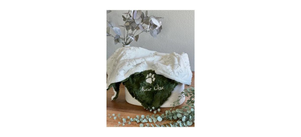 OnePoshPup Personalized Paw Print Dog Blanket in green and white, inside a basket