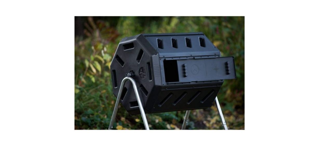black outdoor tumbling composter in front of a bush